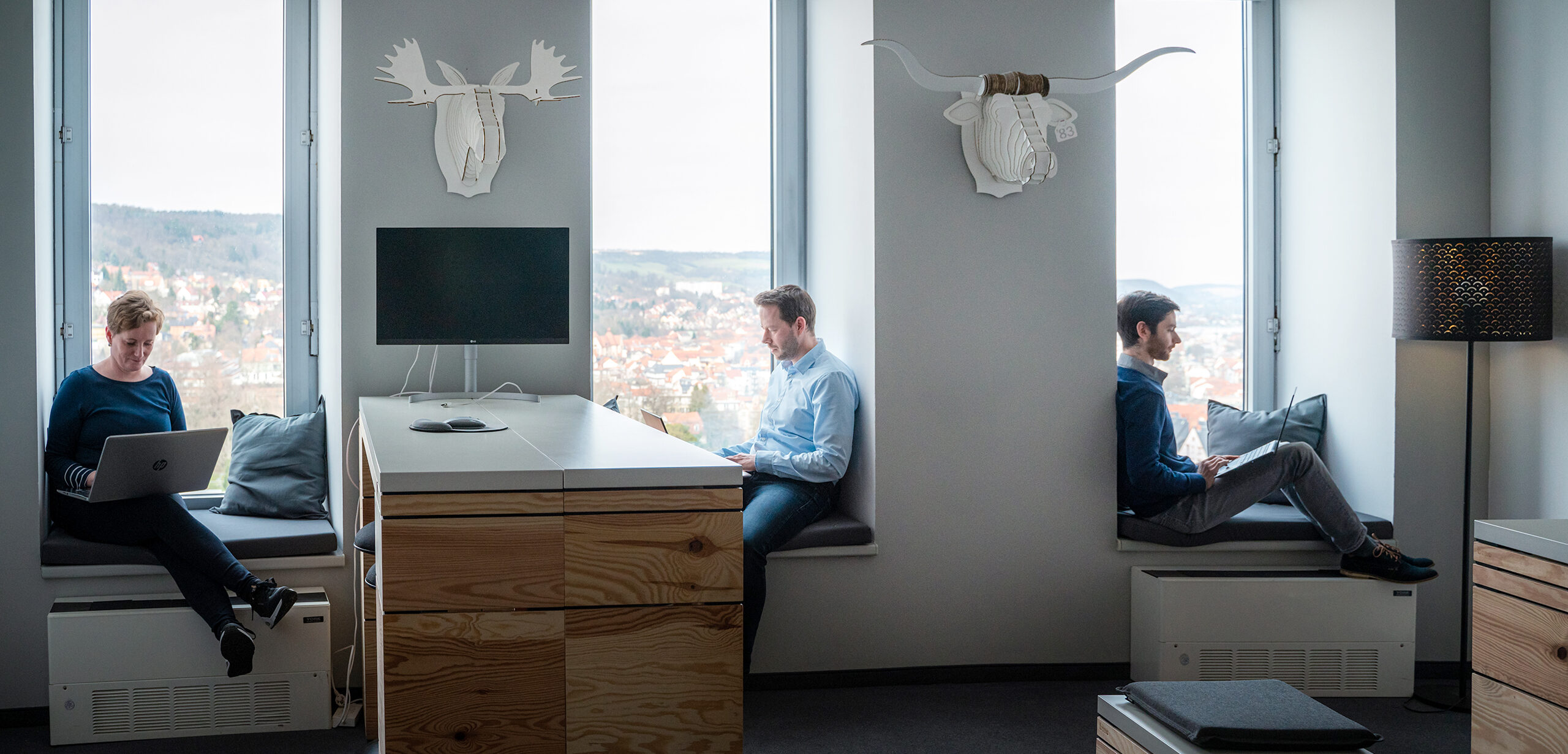 Mitarbeitende der Digitalagentur Adignos bei der konzentrierten Arbeit an Laptops in einem modernen Büro.