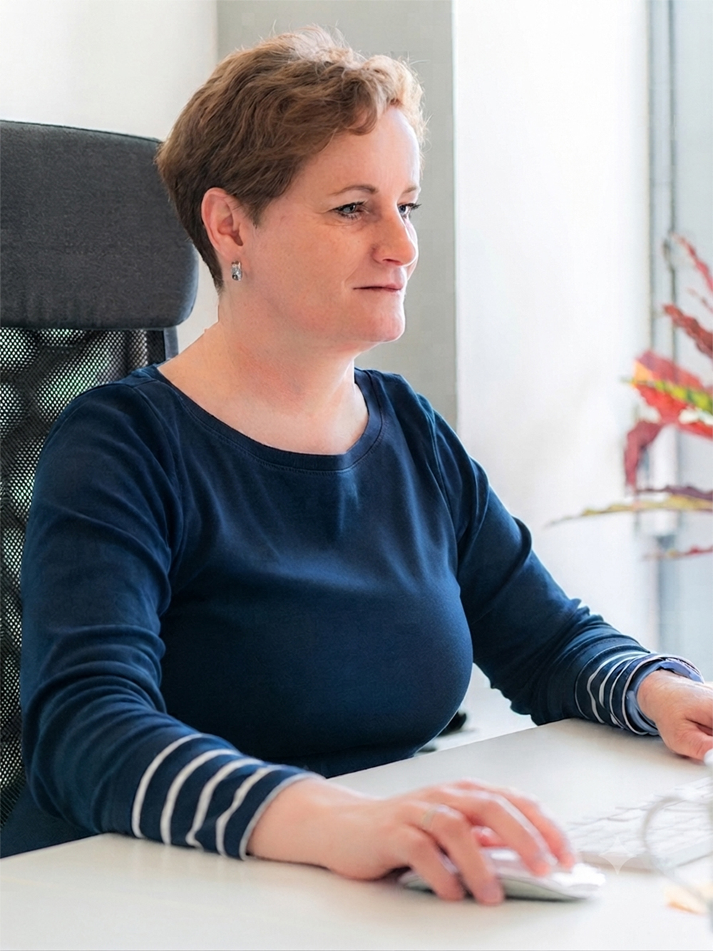 Mitarbeiterin der Digitalagentur Adignos bei der konzentrierten Arbeit am Computer im Büro.